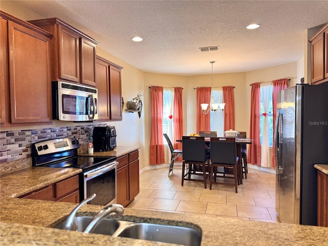 kitchen featuring sink, a notable chandelier, backsplash, decorative light fixtures, and appliances with stainless steel finishes