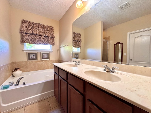 bathroom with tile patterned floors, vanity, separate shower and tub, and a textured ceiling