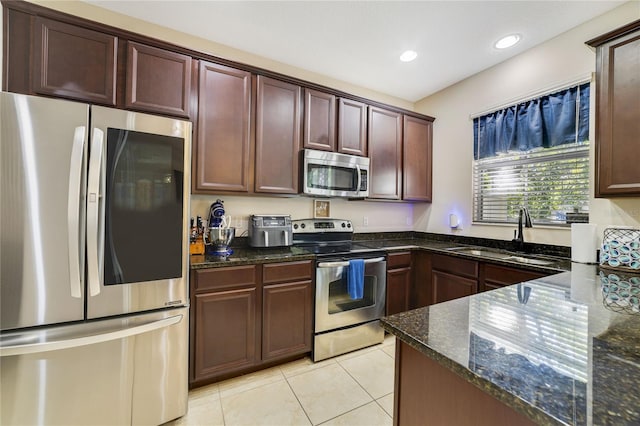 kitchen featuring sink, stainless steel appliances, dark stone counters, and light tile patterned flooring