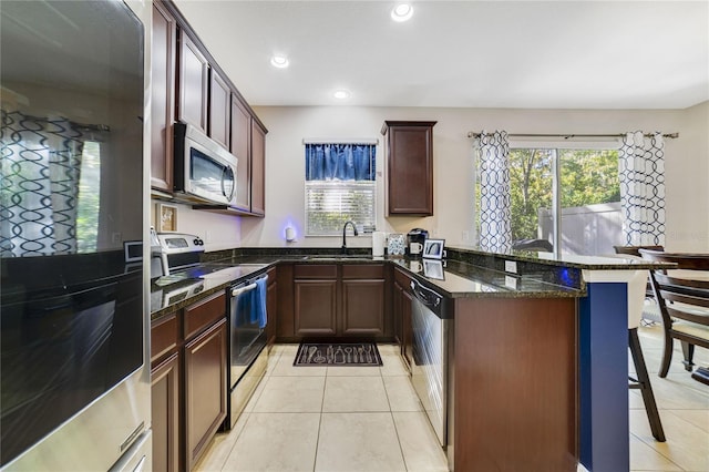 kitchen with appliances with stainless steel finishes, sink, plenty of natural light, and dark stone countertops