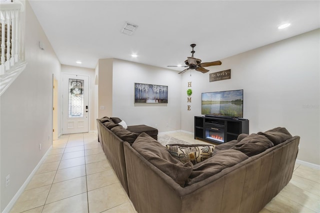 tiled living room with ceiling fan and a fireplace