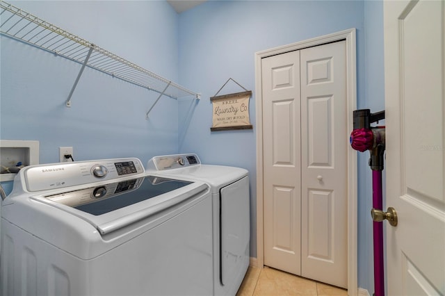 clothes washing area featuring light tile patterned floors and washer and clothes dryer