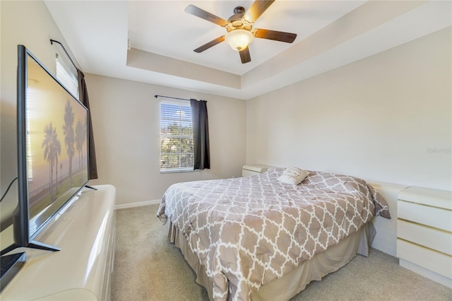 carpeted bedroom featuring ceiling fan and a tray ceiling