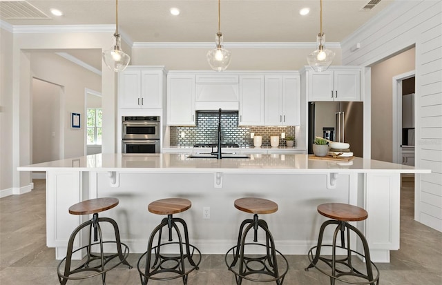 kitchen featuring white cabinets, a kitchen breakfast bar, stainless steel appliances, and a large island