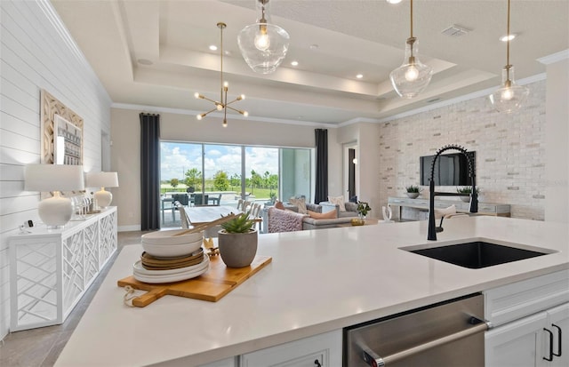 kitchen with a tray ceiling, stainless steel dishwasher, white cabinetry, and sink