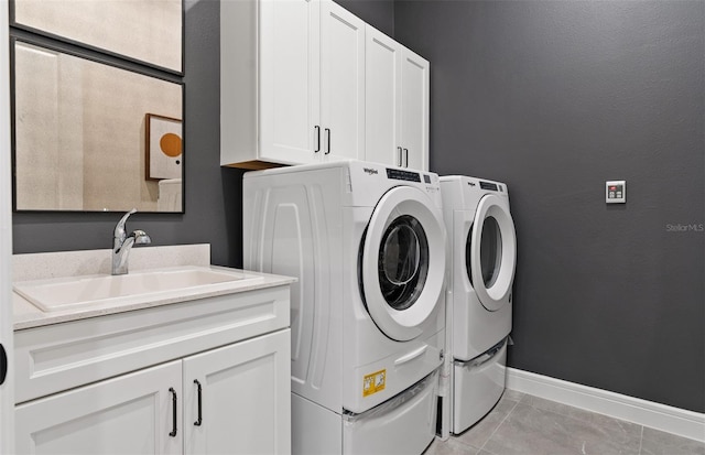 clothes washing area with washer and dryer, light tile patterned floors, cabinets, and sink