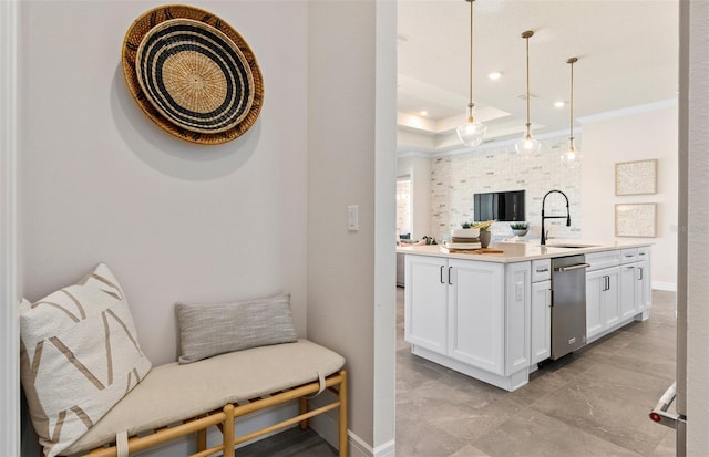 kitchen featuring white cabinetry, sink, stainless steel dishwasher, pendant lighting, and ornamental molding