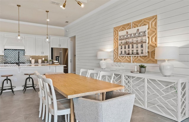 dining room with tile patterned floors, wooden walls, and ornamental molding