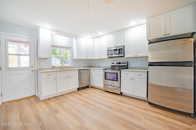 kitchen with white cabinets, sink, light wood-type flooring, and stainless steel appliances