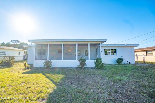 view of front of house featuring a sunroom and a front lawn