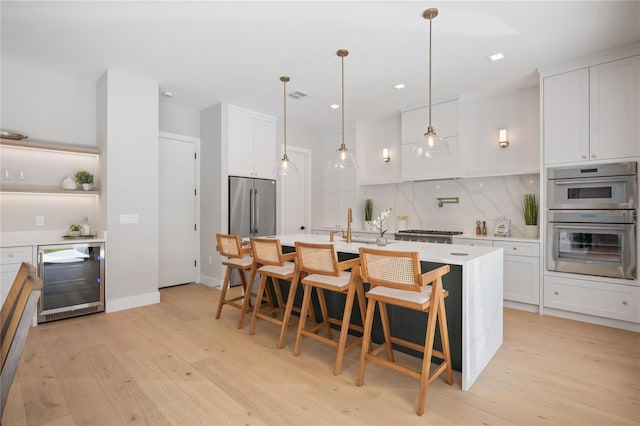 kitchen with appliances with stainless steel finishes, light wood-type flooring, white cabinetry, and wine cooler