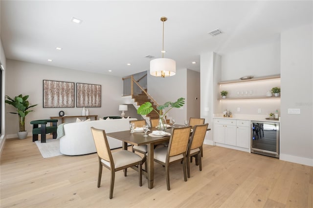 dining area featuring bar, beverage cooler, and light hardwood / wood-style floors