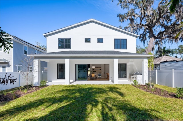 back of property with a lawn, area for grilling, and a patio