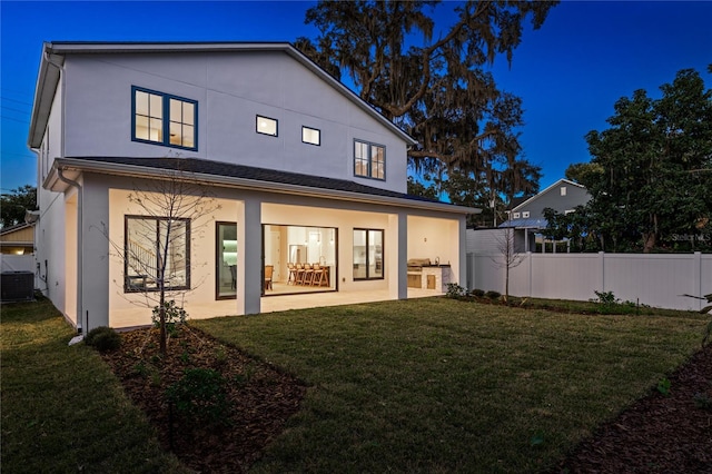 back of property featuring a lawn, central AC unit, exterior kitchen, and a patio