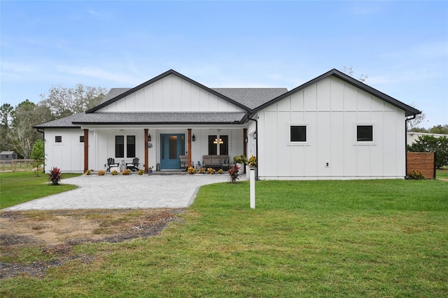 rear view of property featuring covered porch and a lawn