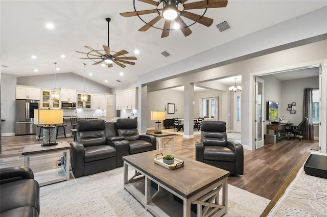 living room featuring ceiling fan with notable chandelier, wood-type flooring, and lofted ceiling