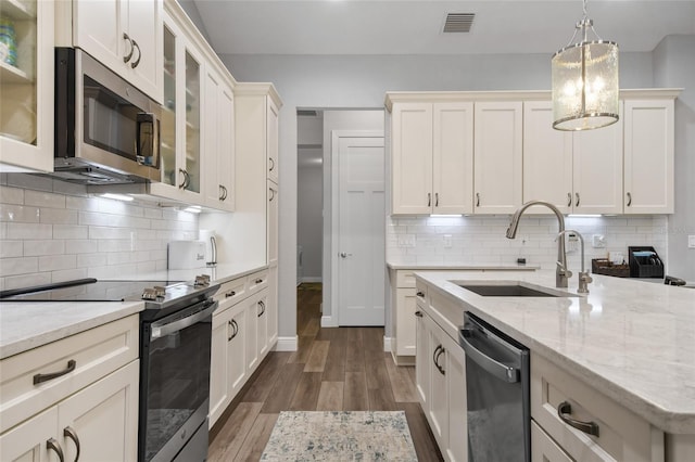 kitchen with pendant lighting, sink, dark hardwood / wood-style floors, decorative backsplash, and appliances with stainless steel finishes