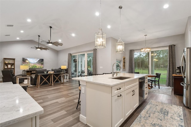 kitchen featuring pendant lighting, hardwood / wood-style floors, lofted ceiling, white cabinetry, and stainless steel appliances