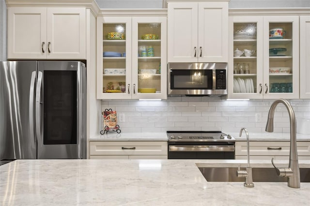 kitchen featuring light stone counters, sink, stainless steel appliances, and tasteful backsplash