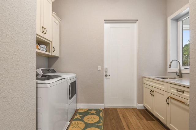 laundry area with cabinets, light hardwood / wood-style floors, washing machine and dryer, and sink