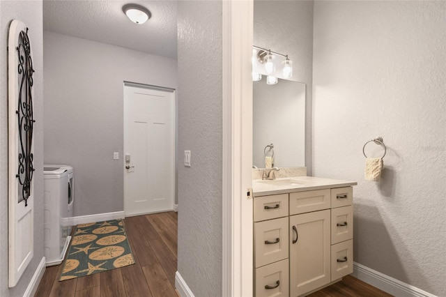 bathroom featuring separate washer and dryer, vanity, wood-type flooring, and a textured ceiling