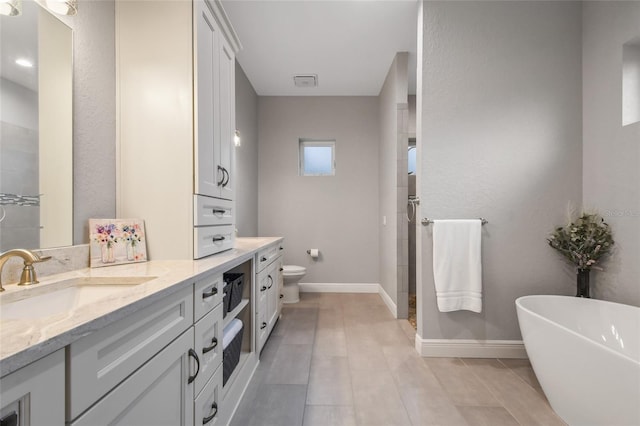 bathroom with tile patterned flooring, vanity, a tub to relax in, and toilet