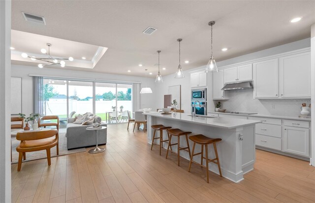 kitchen with a center island with sink, white cabinets, light hardwood / wood-style floors, and appliances with stainless steel finishes