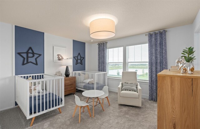 bedroom with a crib, a textured ceiling, and carpet flooring