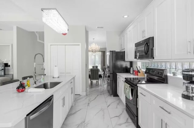 kitchen with light stone counters, sink, black appliances, white cabinetry, and an island with sink