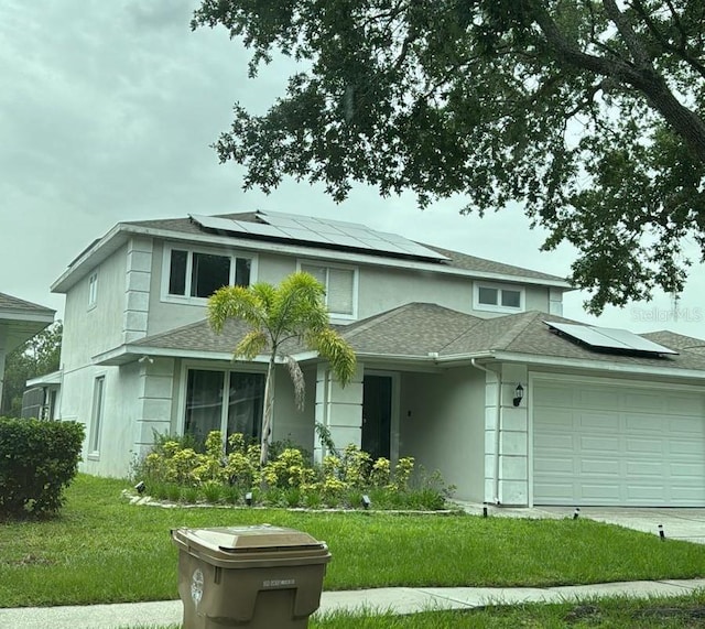 view of front of home with a garage, a front yard, and solar panels