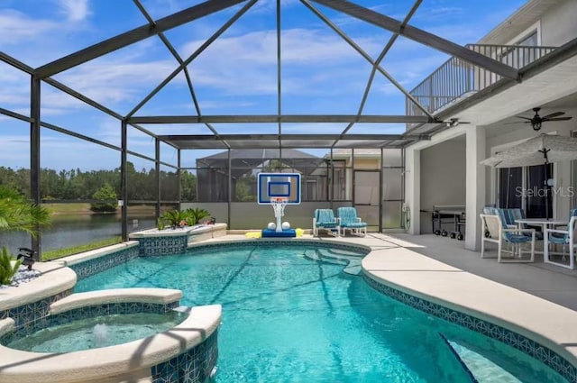 view of pool featuring a patio area, an in ground hot tub, a water view, and glass enclosure