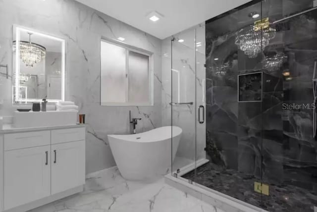 bathroom with an inviting chandelier, vanity, and shower with separate bathtub