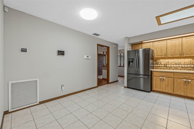 kitchen with stainless steel fridge, a textured ceiling, tasteful backsplash, and light tile patterned flooring