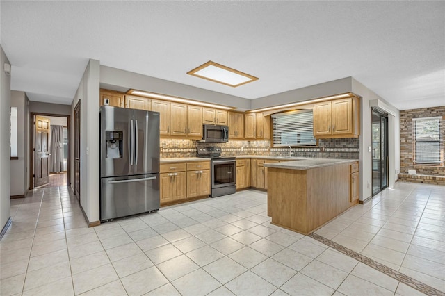 kitchen with kitchen peninsula, appliances with stainless steel finishes, tasteful backsplash, and light tile patterned floors