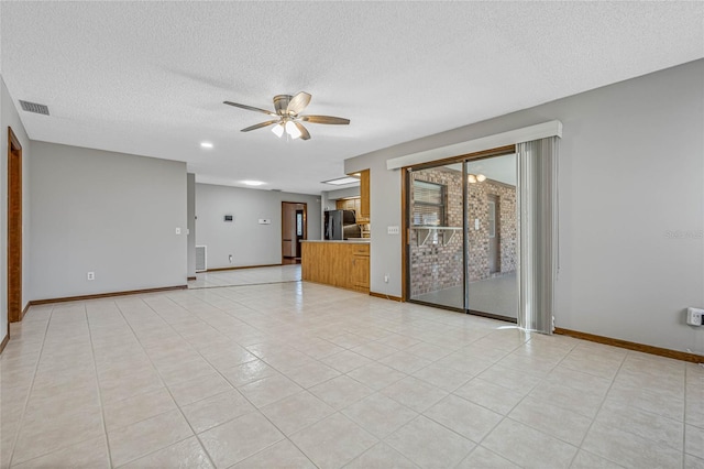 empty room featuring ceiling fan, light tile patterned floors, and a textured ceiling