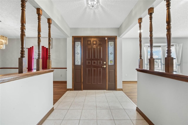 foyer entrance featuring light wood-type flooring, a textured ceiling, and a notable chandelier