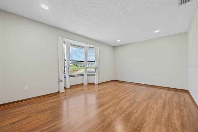 empty room with wood-type flooring and a textured ceiling