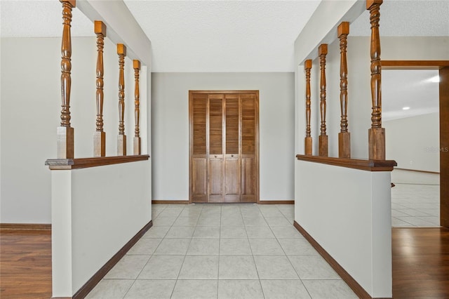 hall featuring light tile patterned floors and a textured ceiling