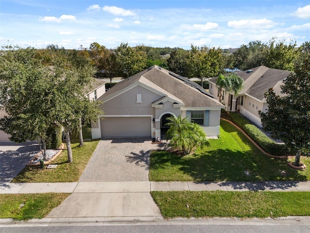 ranch-style home featuring a garage, a shingled roof, decorative driveway, a front lawn, and stucco siding