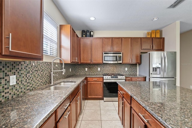 kitchen featuring light tile patterned floors, visible vents, dark stone counters, stainless steel appliances, and a sink