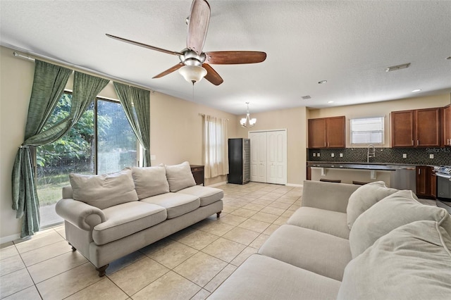 tiled living room with a textured ceiling, ceiling fan with notable chandelier, and sink