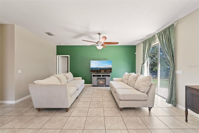 living room featuring ceiling fan, light tile patterned flooring, and a textured ceiling