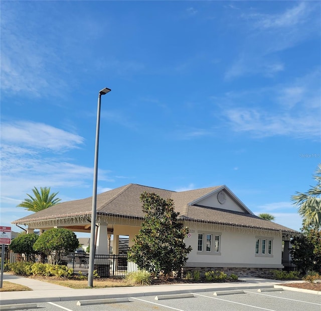 view of building exterior with uncovered parking and fence