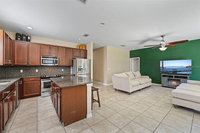 kitchen with appliances with stainless steel finishes, open floor plan, backsplash, and a kitchen breakfast bar