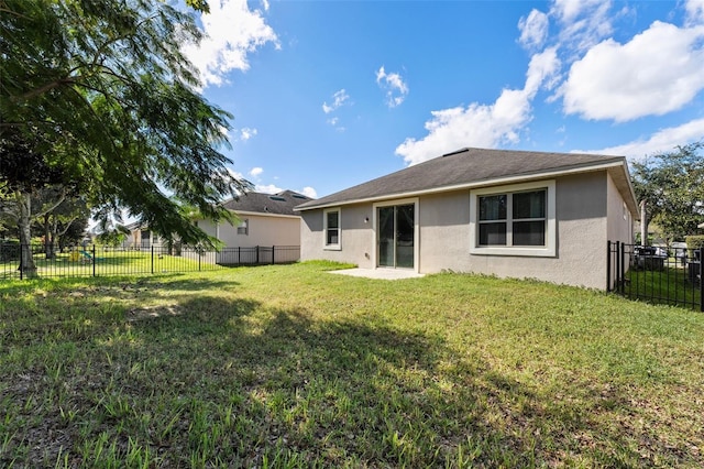 rear view of house with a yard, a fenced backyard, and stucco siding