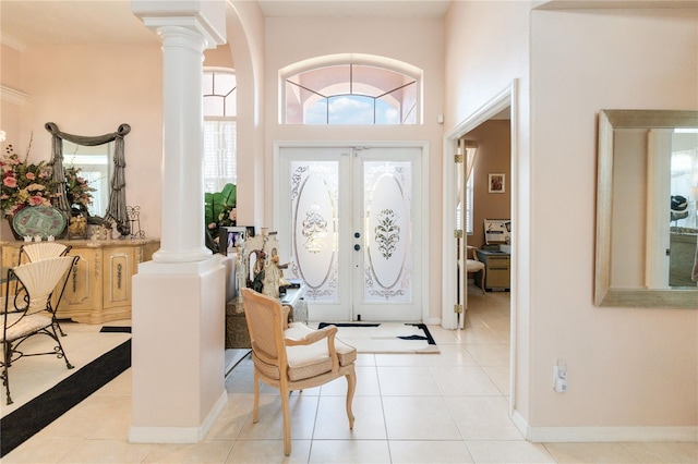 foyer entrance with light tile patterned floors, decorative columns, and french doors