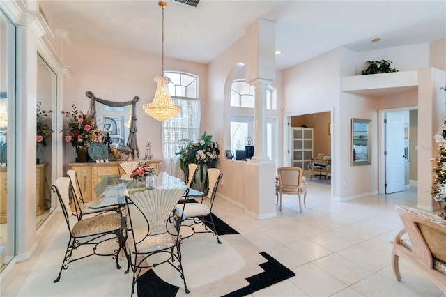 tiled dining room with a high ceiling, a chandelier, and ornate columns