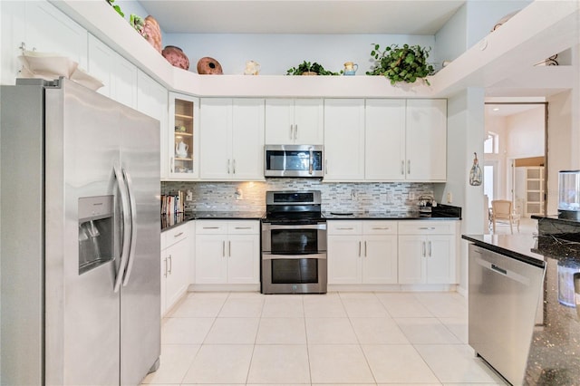 kitchen with white cabinetry, appliances with stainless steel finishes, light tile patterned floors, and backsplash