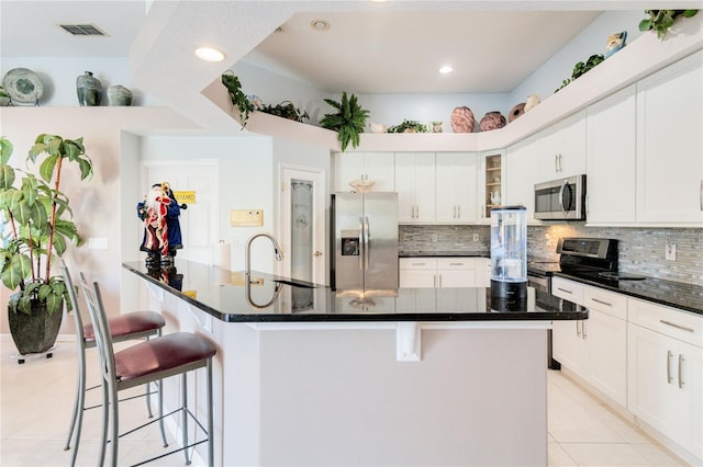 kitchen with sink, a kitchen bar, white cabinets, and appliances with stainless steel finishes