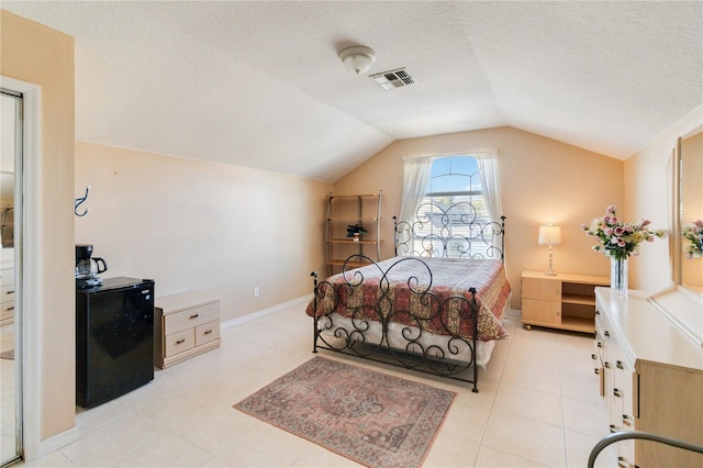 bedroom featuring lofted ceiling, light tile patterned floors, and a textured ceiling